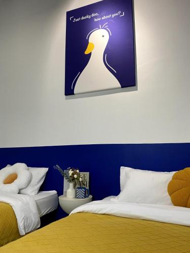 a bedroom with two beds and a picture of a penguin at 嘿夏天 HeySummer-13pax l 200mJetty l Netflix l Games l Youtube in Mersing