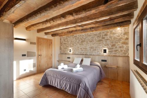 a bedroom with a bed and a stone wall at Cal Trumfet in Caserras