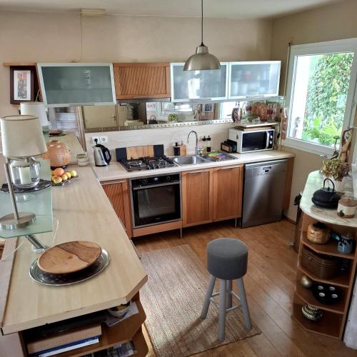 une cuisine avec des armoires en bois et un comptoir dans l'établissement Chambre et jardin, à Bayonne