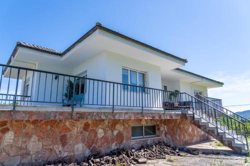 a house with a balcony and a stone wall at Preciosa casa rural en Nava in Sienra