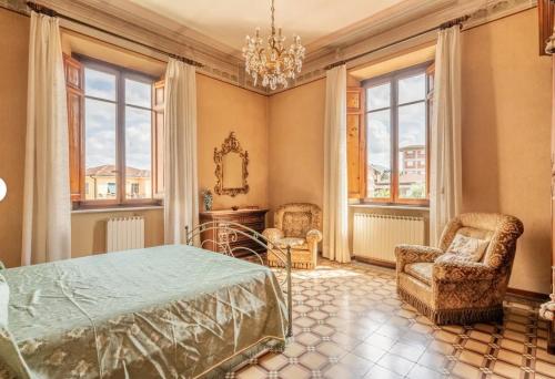 a bedroom with a bed and two chairs and a mirror at Guest House Villa Lenzi - Dimora Storica in Lucca