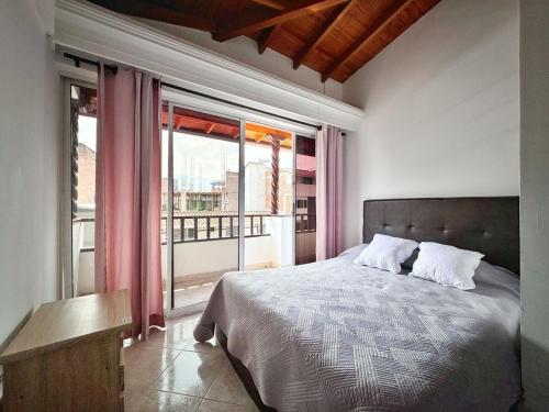Un dormitorio con una cama y una ventana grande. en Apartamento cerca a Estadio con balcon y 5 habitaciones, en Medellín