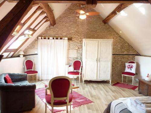 Cette chambre mansardée comprend des chaises rouges et un canapé. dans l'établissement Le Plessis, Stone Farmhouse Loft with Gardens and Pool, à Neuillé-le-Lierre