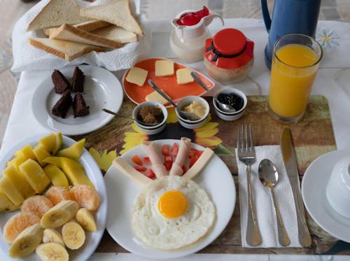 a breakfast table with eggs and fruit and toast at Casa Mariana in Las Terrenas