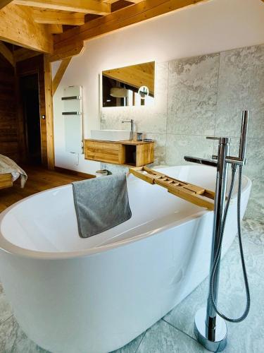une baignoire blanche dans une salle de bain avec un lavabo dans l'établissement Chalet Monarch - Les Carroz - Sauna, Spa & vue Montagnes, à Arâches-la-Frasse