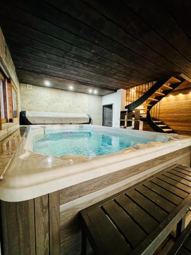 Un grand bain à remous est installé dans un bâtiment avec un escalier. dans l'établissement Chalet Monarch - Les Carroz - Sauna, Spa & vue Montagnes, à Arâches-la-Frasse
