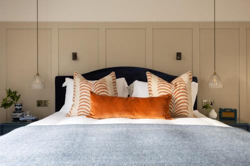 a bed with orange and white pillows on it at The Blue Pigeons Hotel and Restaurant in Worth