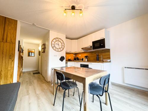 une cuisine avec une table et des chaises et une horloge au mur dans l'établissement Appartement Proche Des Pistes By TerraAlpina, à Saint-Gervais-les-Bains