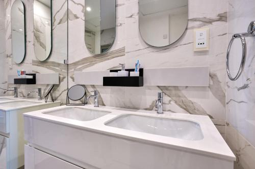 a white bathroom with two sinks and mirrors at Coastal One Bedroom Retreat with direct Breathtaking Sea Views in Sliema