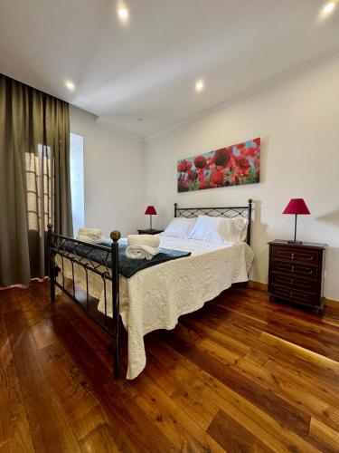 a bedroom with a bed and a painting on the wall at Casa do Rosário - Ribeira Grande in Ribeira Grande