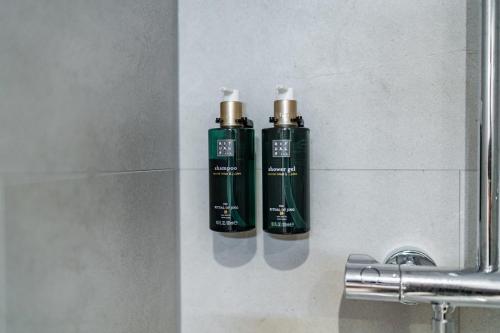 two green bottles on a wall next to a sink at Martini Hotel in Groningen