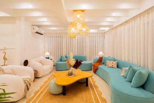 a living room with blue couches and a table at ELIVAAS House of Neptune - 3 BHK Cottage with Terrace & Gazebo on the Beach in Morjim