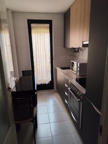 a small kitchen with a stove and a microwave at Apartamentos Turisticos de Soria Collado 3 in Soria