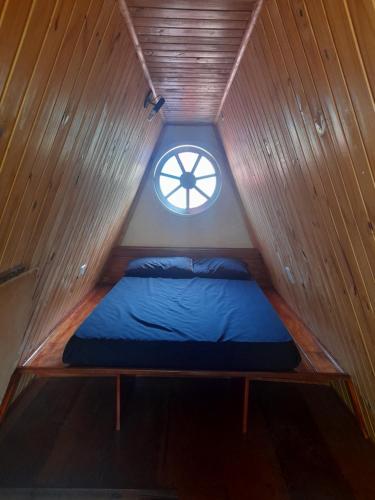 a bed in a small room with a window at Chalés Monções in Ubatuba
