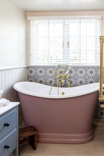a bath tub in a bathroom with a window at The Blue Pigeons Hotel and Restaurant in Worth