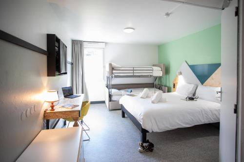 a room with two beds and a desk with a laptop at greet Hôtel Montbéliard in Montbéliard