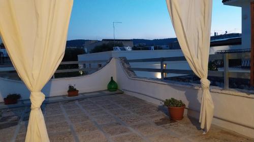 a balcony with curtains and plants on a building at LA CASETTA in puglia in Montalbano