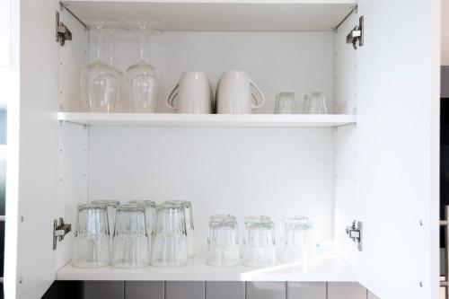 a white cabinet filled with glass jars and vases at Luxurious 1BR Gem Steps from the Action in Pflugerville