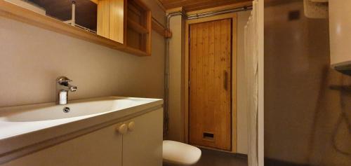 a bathroom with a white sink and a wooden door at Sauna | Wi-Fi | Terrace | Wood stove | Cable TV in Lofsdalen