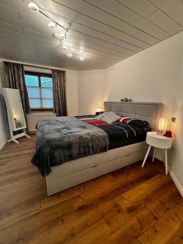 a bedroom with a large bed and a wooden floor at Auszeit am Riedbach in Lindenberg im Allgäu