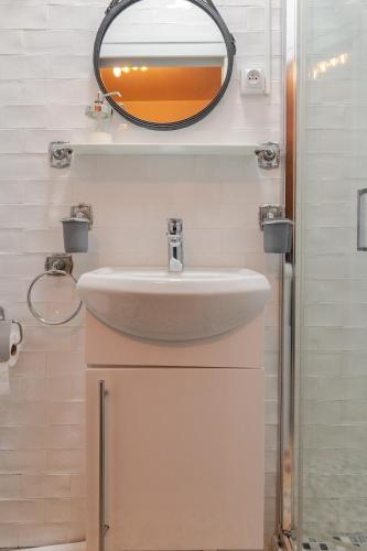 une salle de bain avec un lavabo et un miroir dans l'établissement Studio Paris - Métro 7 Cadet - Quartier Faubourg-Montmartre, à Paris