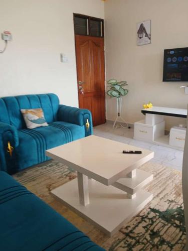 a living room with a blue couch and a coffee table at Logan White Cozy home in Mombasa