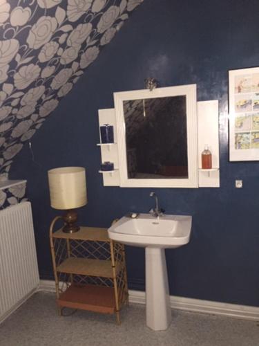 une salle de bains bleue avec lavabo et fenêtre. dans l'établissement Brémailles41, à Onzain
