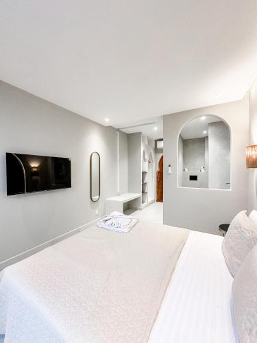 a white bedroom with a white bed and a tv at La Finca - 3BR Seaside Villa with Private Pool & BBQ in Tangier