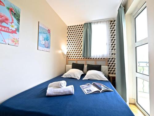 - une chambre avec un lit bleu et 2 serviettes dans l'établissement Apartment Village Cap Estérel - Le Village-82 by Interhome, à Agay