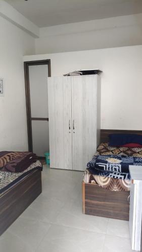 a bedroom with two beds and a cabinet in it at Capsule Hostel And PG Services in Gorakhpur