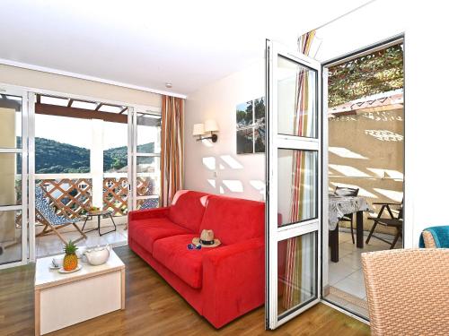un salon avec un canapé rouge et un balcon dans l'établissement Apartment Village Cap Estérel - L'Esquinade-110 by Interhome, à Agay