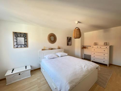 a bedroom with a white bed and a dresser at "Le Cœur de la Vieille Ville" in Porrentruy