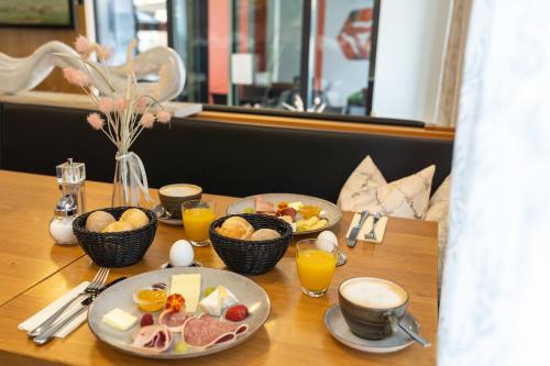 a table with plates of food and cups of orange juice at Stadthotel Reich in Mellrichstadt