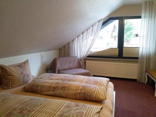 a hotel room with two beds and a chair and a window at Ferienhaus am Sonnenhang in Willingen