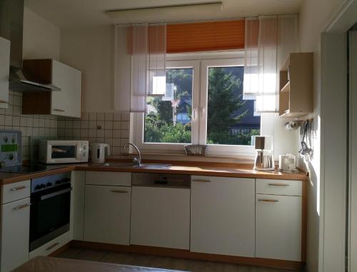 a kitchen with white cabinets and a window at Ferienhaus am Sonnenhang in Willingen