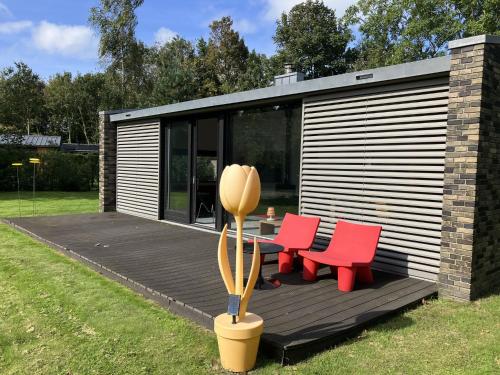a cabin with two red chairs and a table on a deck at Holiday Home Villa Vrijheid by Interhome in Hollum