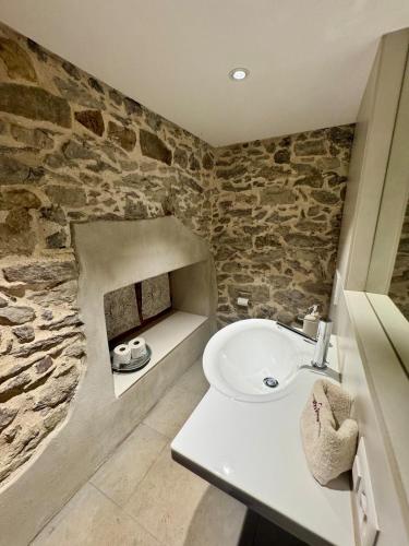a bathroom with a sink and a stone wall at Living on a animal sanctuary in Schönenberg