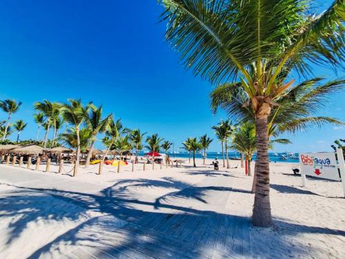 a palm tree on a sandy beach with the ocean at GLOBALSTAY Cocotal Condo in Punta Cana in Punta Cana