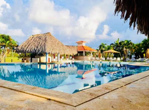 a swimming pool at a resort with a thatch roof at GLOBALSTAY Cocotal Condo in Punta Cana in Punta Cana