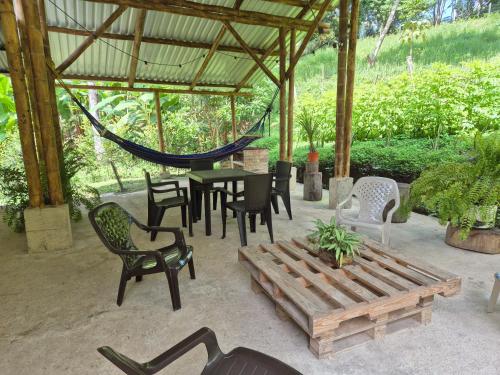 a patio with a table and chairs and a hammock at Cabaña Campestre de descanso in Melgar