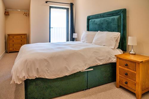 a bedroom with a large bed with a green headboard at Little Rissington - Barn Seven in Little Rissington