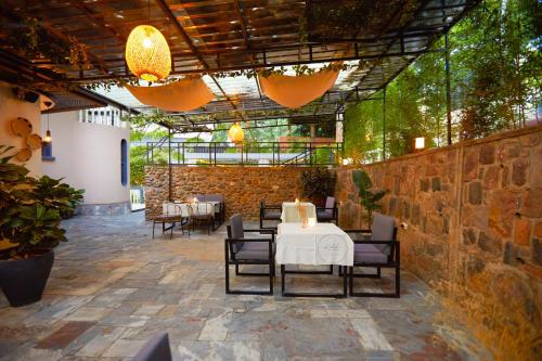 a restaurant with a table and chairs and a stone wall at Kalih Villa in Kigali
