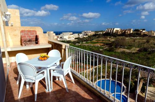 einen Balkon mit einem Tisch, Stühlen und Meerblick in der Unterkunft GozoPride Penthouse in Qala