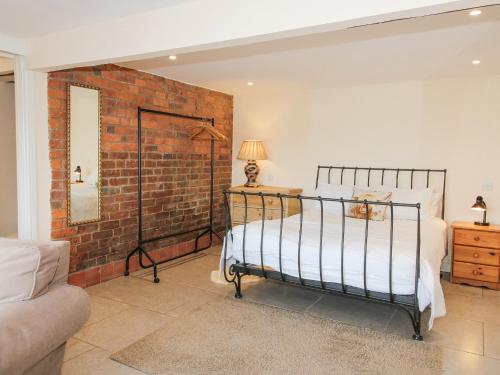 a bedroom with a bed and a brick wall at Millstone Cottages - Granary Cottage in Shrewsbury