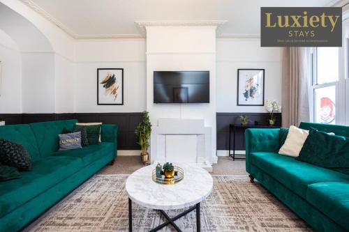 a living room with green couches and a table at Gorgeous & Stylish 3BR Home HIGH STREET LOCATION by Luxiety Stays Serviced Accommodation in Chelmsford
