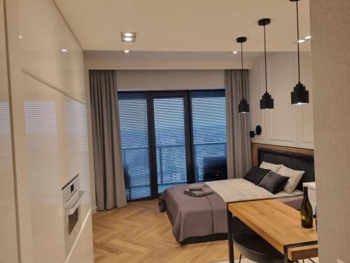 a bedroom with a bed and a desk and a table at Hanza Tower City View 13th floor in Szczecin