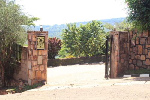 a gate with a sign on it next to a stone wall at REBERO RESORT Ltd in Kigali