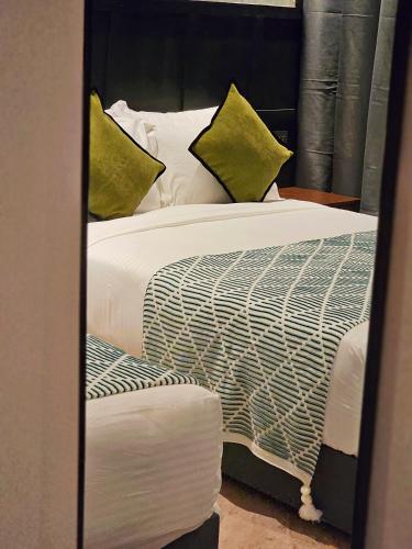 a bedroom with a bed with white sheets and green pillows at Carnarvon Suites in George Town