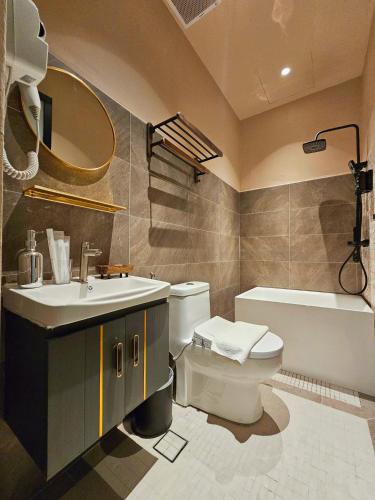 a bathroom with a toilet and a sink and a tub at Carnarvon Suites in George Town