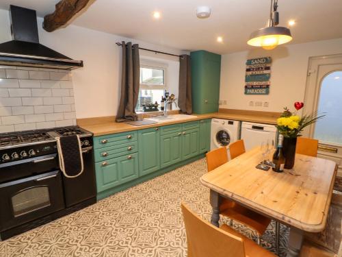a kitchen with green cabinets and a wooden table at Seahaven in Maryport